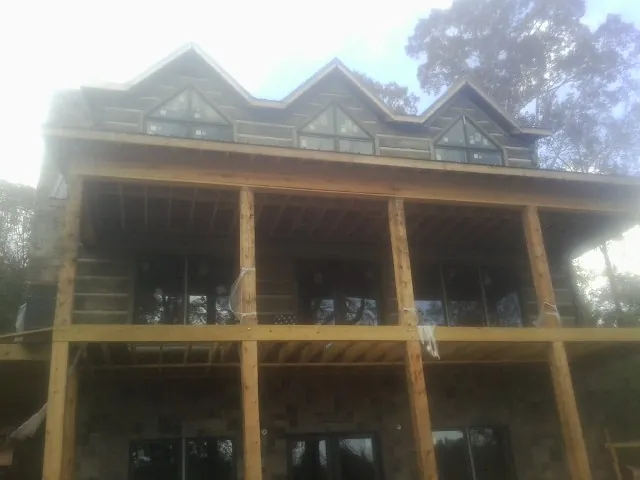 Dormers and porch framing on a large log home under construction — Roof Coating work by our crew in Oskaloosa